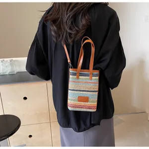 Detalle del mini bolso de paja tejido a rayas coloridas con asa de cuero en modelo
