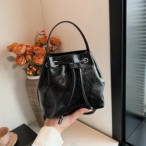 Detail of black cracked texture faux leather bucket bag with silver eyelets and drawstring