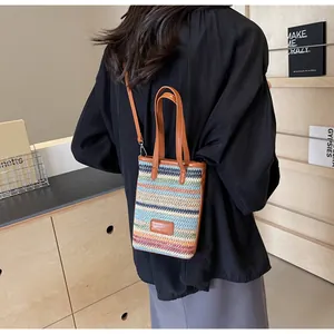 Detalle de bolso de paja de rayas coloridas con correas de cuero en una modelo mujer