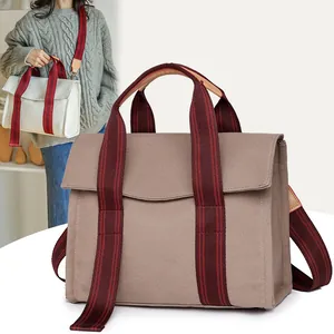 Large canvas tote bag with striped straps in brown and white shown on model