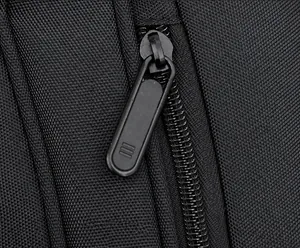 Close-up of smooth matte black metal zipper pull on durable nylon crossbody bag