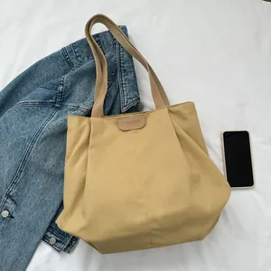 Detail of khaki canvas tote bag featuring leather handles and 'FASHION' embossed patch