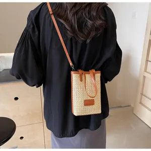 Detalle de bolso de paja trenzada con correa y ribete de cuero marrón para verano