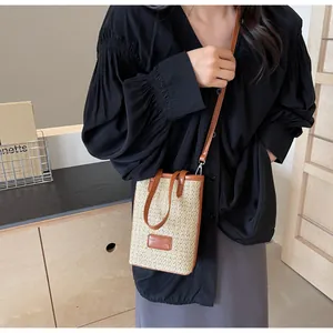 Detalle de mini bolso de paja tejida con ribete de cuero marrón y etiqueta de moda