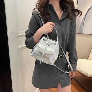 Detail view of silver metallic bucket bag with bow decoration and drawstring closure