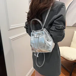Silver metallic bucket bag with pleated texture and drawstring closure on model