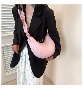 Borsa a mezzaluna rosa trapuntata con tracolla a volant, indossata da una modella chic