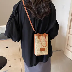 Minibolso bandolera de paja con ribete de cuero marrón usado por modelo para las vacaciones