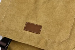 Detailed close-up of canvas texture and brown leather patch on the student backpack