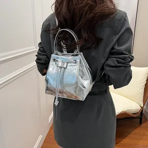 Detail of metallic silver drawstring bucket backpack with shiny textured synthetic leather