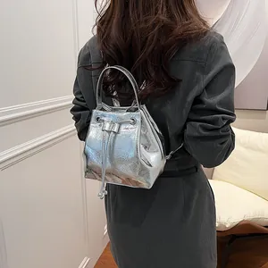 Silver mini bucket backpack with metallic wrinkled texture and drawstring closure on model