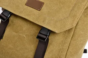 Detailed close-up of mustard yellow canvas backpack with leather patch and buckle