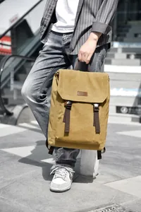 Detail of khaki canvas backpack with brown leather strap closures and flap cover design