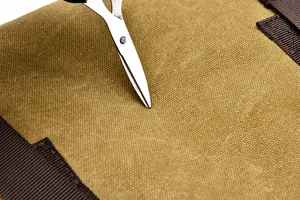 Macro detail of scratch-resistant canvas fabric showing durability with a metal tool test