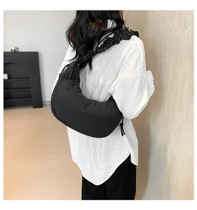 Dettaglio di una borsa hobo nera a pieghe indossata da una modella in una stanza