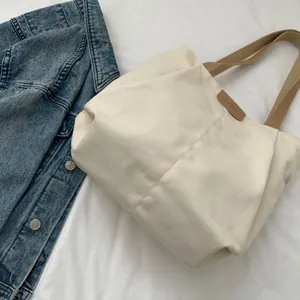 Detailed close-up of a cream canvas tote bag featuring khaki straps and fashion label