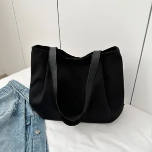 Detail of black canvas tote bag showing the fashion embossed logo and leather handles