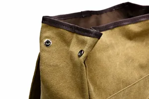 Detail of khaki canvas backpack featuring premium silver metal button and reinforced trim
