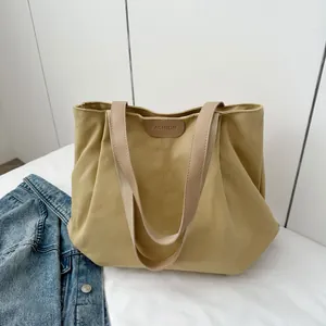 Detail of khaki canvas tote bag featuring a leather patch with embossed fashion text