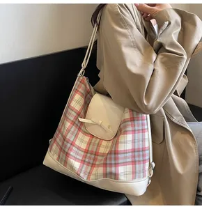 Seitenansicht der rosa karierten Tasche mit Lederschleife auf khakifarbenem Mantel
