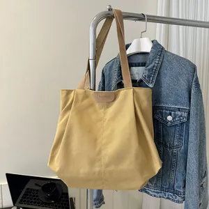 Detail of the ginger canvas tote bag featuring a leather patch and durable brown handles