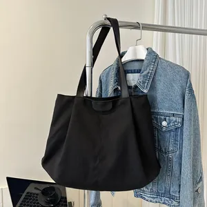 Detail of black canvas tote bag with FASHION leather patch and reinforced stitching