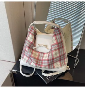 Detail eines roten karierten Rucksacks mit weißer Lederklappe und Schleifendesign