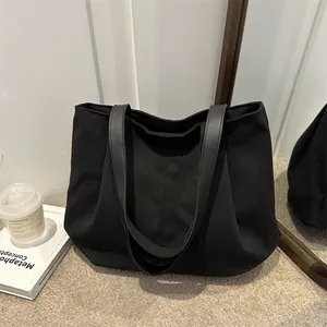 Large black canvas tote bag with leather straps for daily commute in French minimalist style