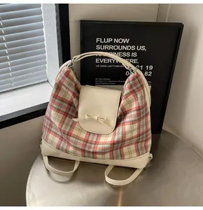 Detail der karierten Tragetasche mit Schleifenakzent und Lederbesatz auf Metalltisch