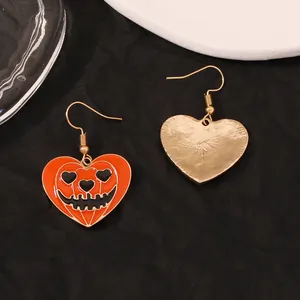 Détail de boucles d'oreilles cœur d'Halloween avec motif visage de citrouille émaillé