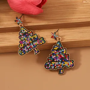 Close-up of golden Christmas tree earrings with colorful rhinestones and star detail