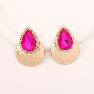 Dettaglio di orecchini a goccia con pietra rosa e texture dorata martellata