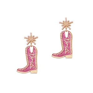 Détail de boucles d'oreilles bottes de cowboy roses avec motif Bride et perles fines