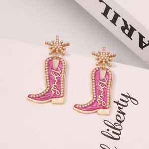 Détail de boucles d'oreilles bottes de cow-boy en émail rose avec perles et texte Bride