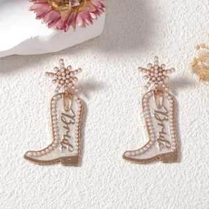 Détail de boucles d'oreilles bottes de cowboy blanches avec perles et texte Bride