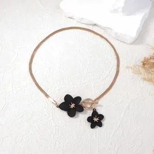 Elegant gold flat snake chain necklace with black flower charms and OT toggle clasp