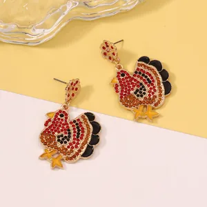 Close-up of sparkling turkey drop earrings with red and orange rhinestones for Thanksgiving