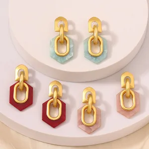 Tres pares de pendientes hexagonales de resina en verde, rojo y rosa sobre podios blancos