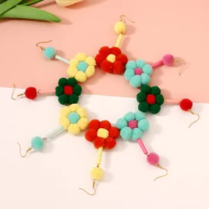 Plano cenital de pendientes de flores con pompones de colores y ganchos dorados