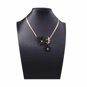 Detail of elegant gold snake chain necklace with black floral charms and OT clasp