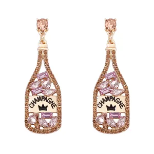 Detalle de aretes de botella de champán con diamantes de imitación rosa y corona