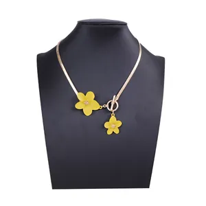 Detail of yellow flower pendant and gold snake chain with OT toggle clasp on model