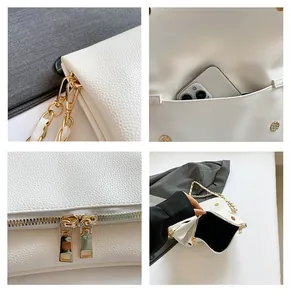 Detail view of white pebbled leather bag featuring gold chain and dual metal zippers
