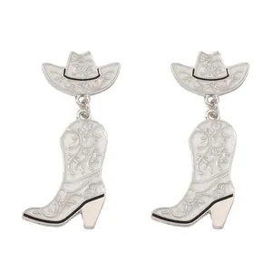 Close-up of silver cowboy hat and boot earrings with white glittery floral enamel details