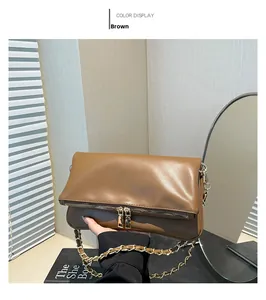 Detail of brown leather crossbody bag with dual gold zippers and chain strap