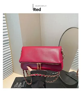 Detail of red pebbled leather shoulder bag with gold zippers and chain strap