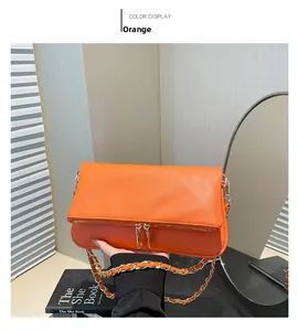 Detail of orange lychee textured leather crossbody bag with golden chain and zipper