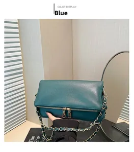 Detail view of the textured leather texture and golden metal chain strap on the blue bag