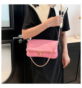 Close-up of pink leather crossbody bag featuring gold zippers and woven metal chain strap