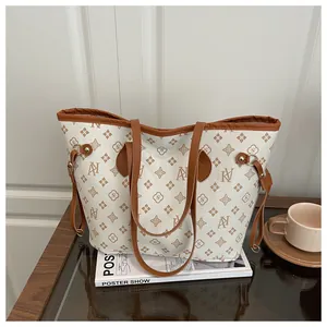 Detailed view of the large capacity printed tote bag with brown leather trim on a table